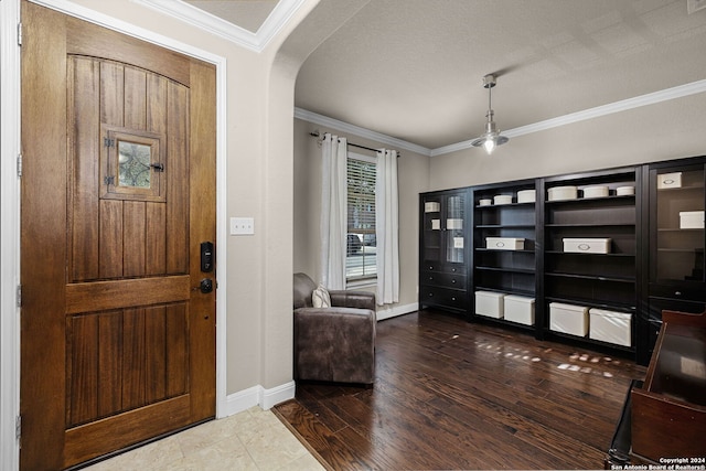 entryway featuring dark wood-type flooring, a textured ceiling, and ornamental molding