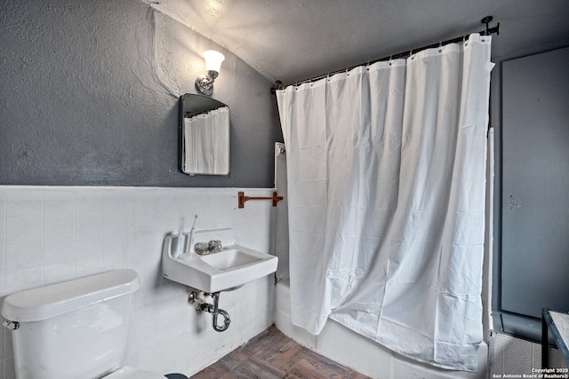 bathroom with shower / bathtub combination with curtain, parquet flooring, a textured ceiling, toilet, and tile walls