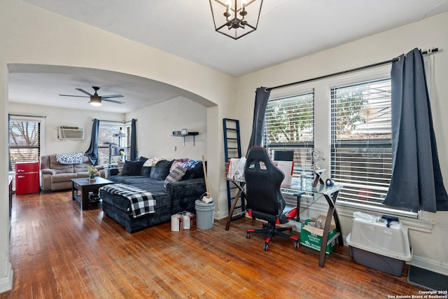 office area featuring a wall mounted air conditioner, ceiling fan with notable chandelier, and hardwood / wood-style flooring