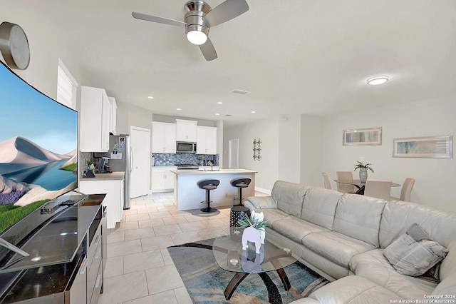 tiled living room featuring ceiling fan and sink