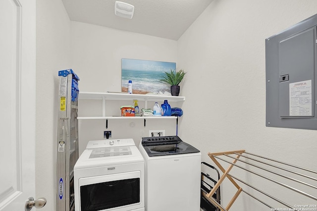 clothes washing area with a textured ceiling, electric panel, and washing machine and clothes dryer