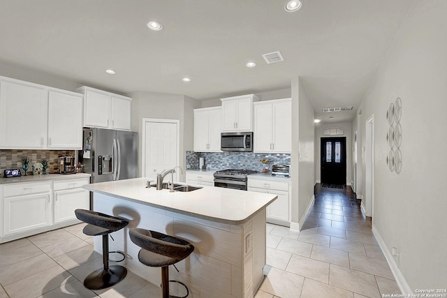 kitchen featuring sink, light tile patterned floors, a center island with sink, white cabinets, and appliances with stainless steel finishes