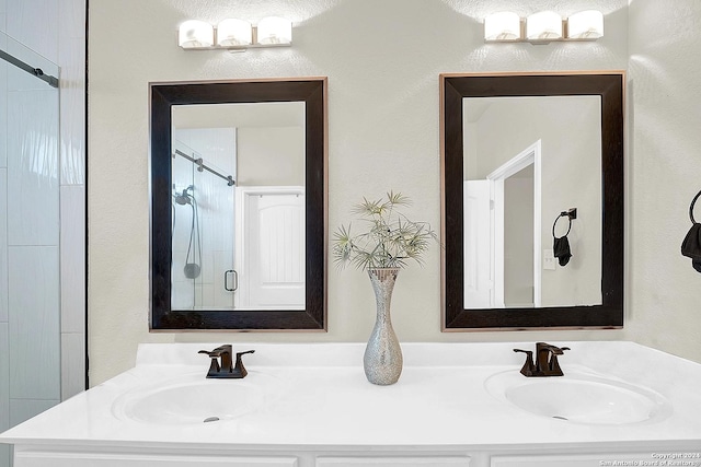 bathroom featuring a shower with door and vanity