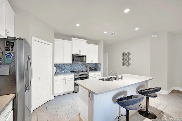 kitchen featuring appliances with stainless steel finishes, white cabinetry, a kitchen island with sink, and sink