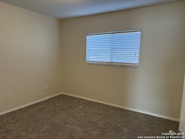 unfurnished room featuring dark carpet