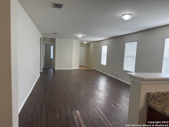 spare room with dark hardwood / wood-style floors, a healthy amount of sunlight, and a textured ceiling