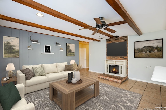 tiled living room with beam ceiling, a brick fireplace, ceiling fan, and wood walls