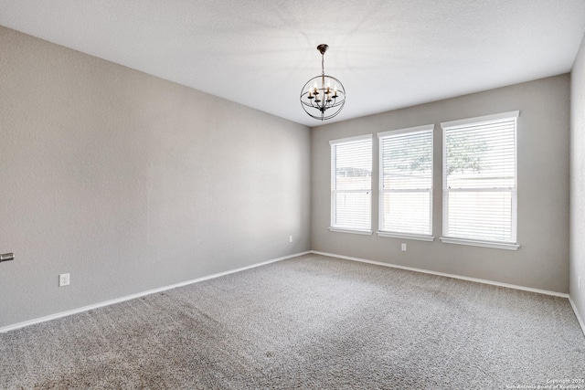 carpeted empty room with a chandelier