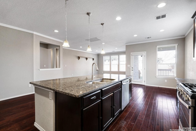 kitchen featuring light stone countertops, stainless steel appliances, sink, a center island with sink, and hanging light fixtures