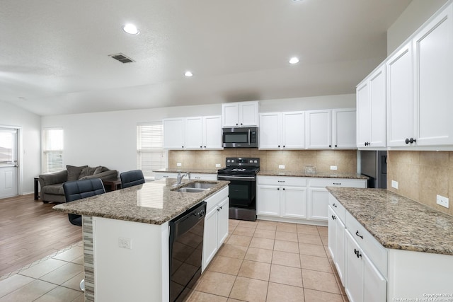 kitchen with sink, black appliances, an island with sink, white cabinetry, and light tile patterned flooring