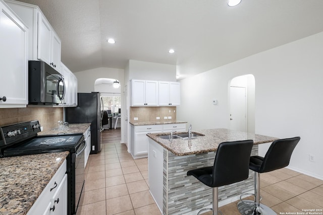 kitchen featuring black electric range oven, white cabinetry, sink, and a breakfast bar area