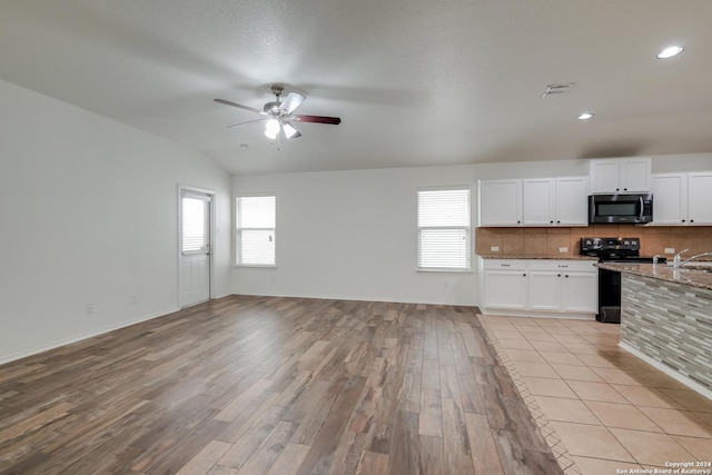 kitchen featuring white cabinets, light stone counters, tasteful backsplash, black electric range, and lofted ceiling