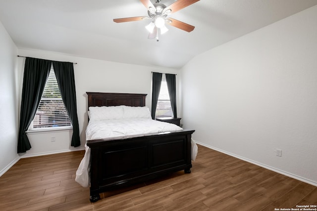 bedroom with dark hardwood / wood-style floors, vaulted ceiling, and ceiling fan