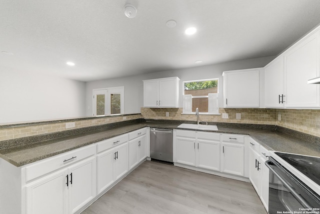 kitchen with white cabinetry, sink, light hardwood / wood-style floors, decorative backsplash, and appliances with stainless steel finishes