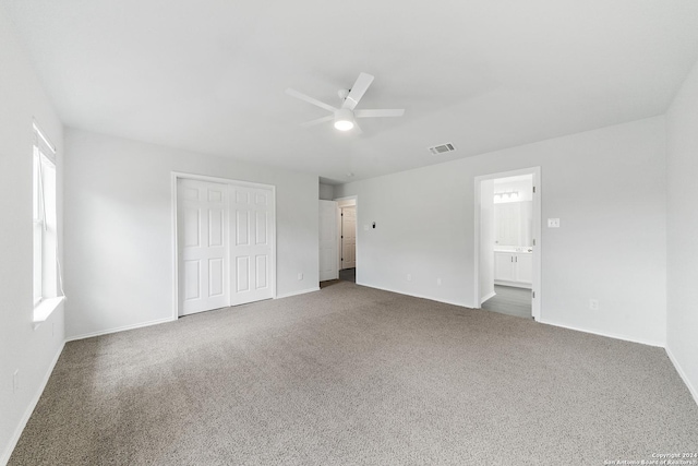 unfurnished bedroom featuring ceiling fan, a closet, carpet, and ensuite bathroom