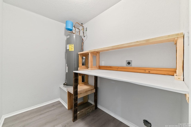 interior space featuring hardwood / wood-style flooring, electric water heater, and a textured ceiling