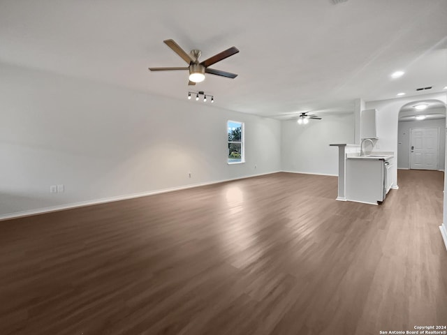 unfurnished living room featuring ceiling fan, sink, and dark wood-type flooring