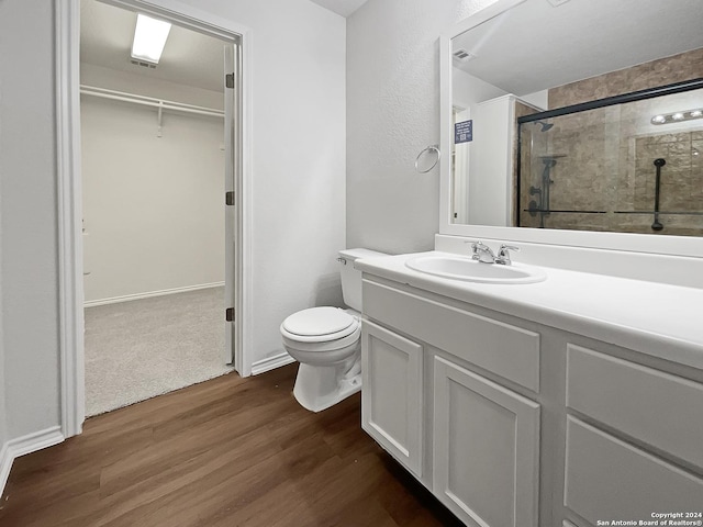 bathroom with toilet, hardwood / wood-style floors, vanity, and walk in shower