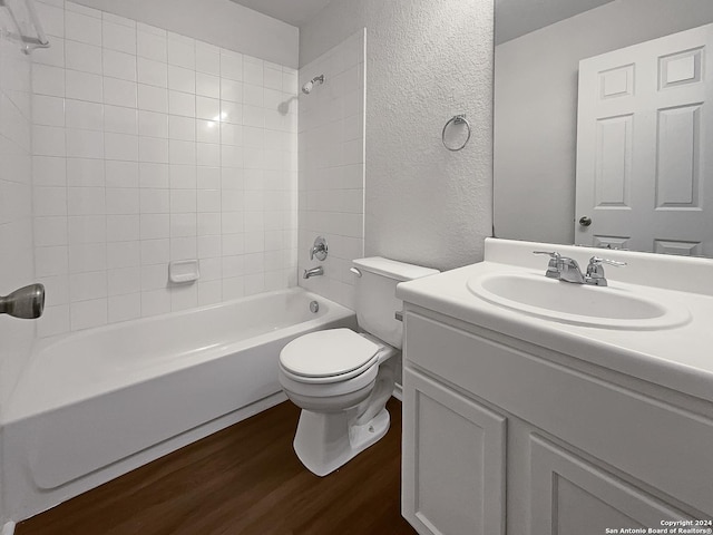 full bathroom featuring vanity, tiled shower / bath combo, hardwood / wood-style flooring, and toilet