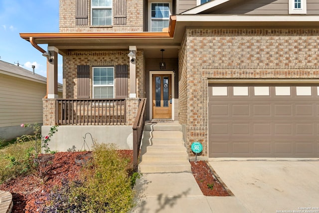 view of exterior entry featuring a porch and a garage