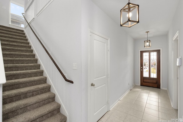 foyer with light tile patterned flooring and an inviting chandelier