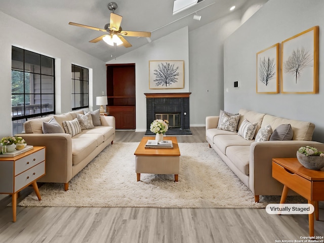 living room featuring a tile fireplace, ceiling fan, light hardwood / wood-style flooring, and lofted ceiling