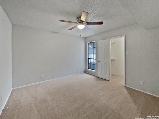 carpeted spare room with a textured ceiling and ceiling fan