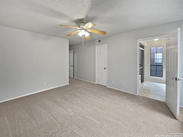 carpeted spare room featuring ceiling fan and a textured ceiling