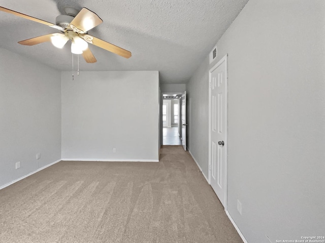 carpeted empty room featuring ceiling fan and a textured ceiling