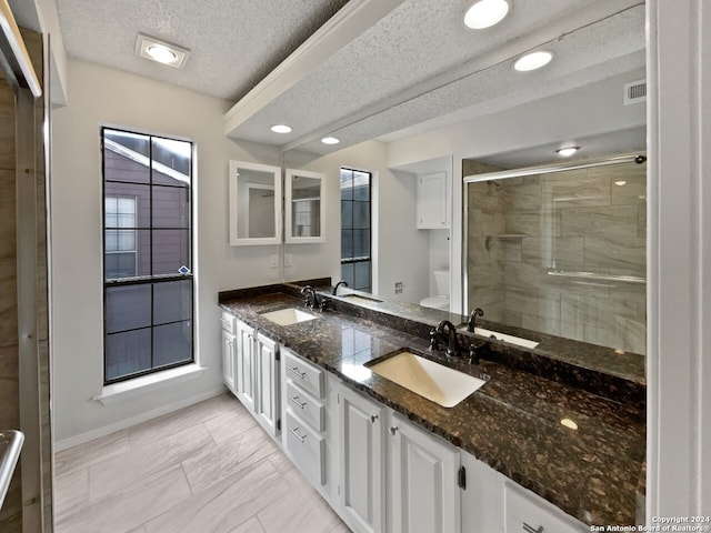 bathroom featuring an enclosed shower, vanity, a textured ceiling, toilet, and plenty of natural light