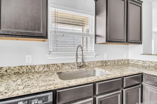 kitchen featuring dishwasher, dark brown cabinetry, light stone countertops, and sink