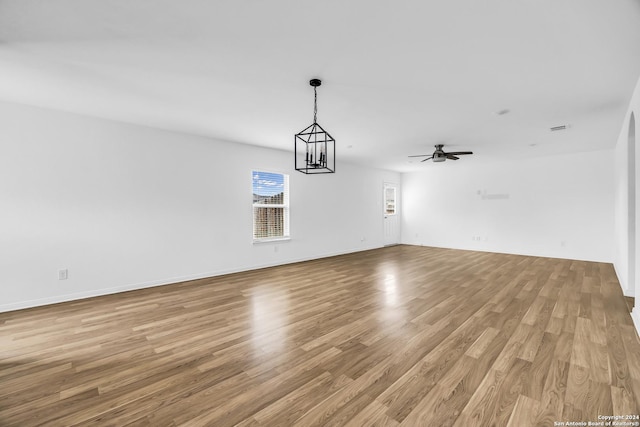 interior space with ceiling fan with notable chandelier and light hardwood / wood-style flooring