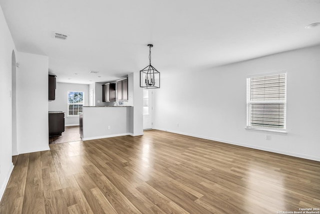 unfurnished living room featuring a notable chandelier and hardwood / wood-style flooring