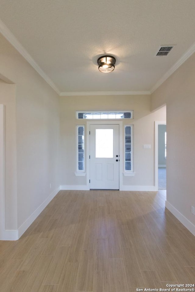 entryway with light wood-type flooring and crown molding