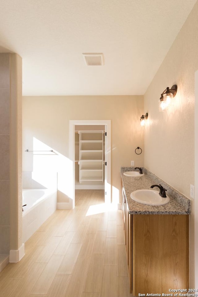 bathroom featuring vanity and tiled bath