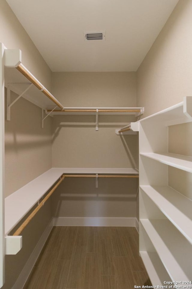 walk in closet with dark wood-type flooring