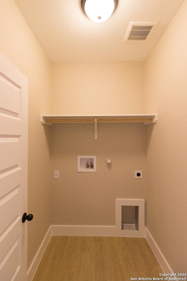 washroom featuring gas dryer hookup, hardwood / wood-style flooring, washer hookup, electric dryer hookup, and a textured ceiling