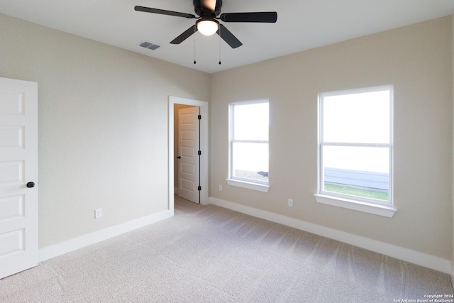 empty room with ceiling fan and light carpet