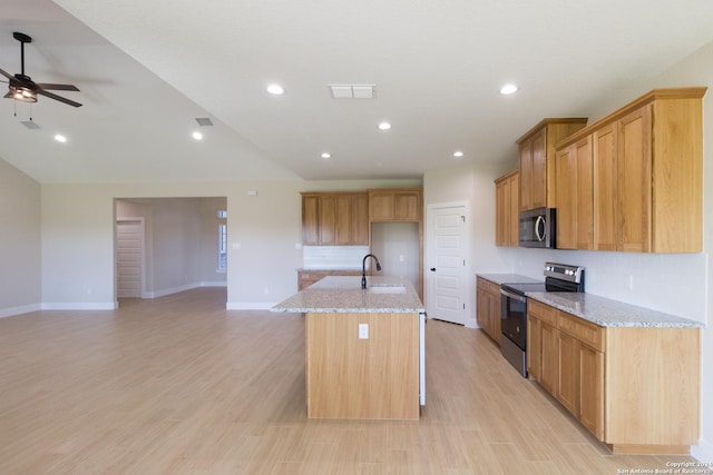 kitchen featuring sink, light stone counters, a center island with sink, appliances with stainless steel finishes, and light hardwood / wood-style floors