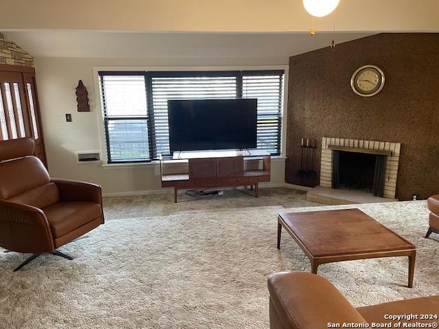 carpeted living room with ceiling fan and a fireplace