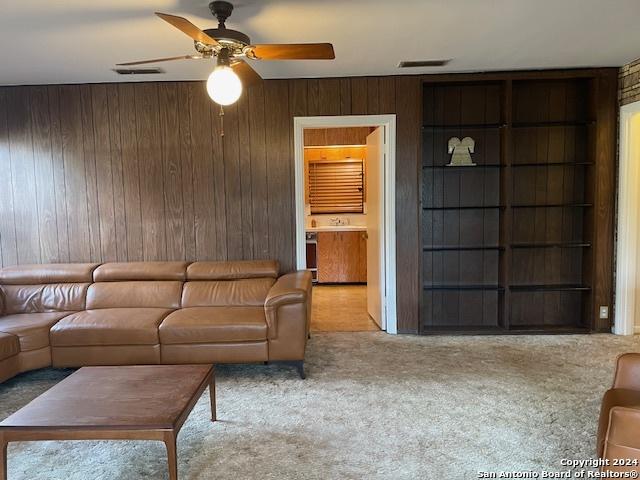 unfurnished living room with light colored carpet, ceiling fan, and wooden walls