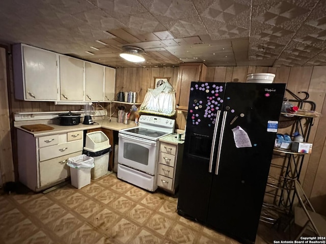 kitchen with black refrigerator with ice dispenser, light parquet floors, white electric range oven, and wood walls