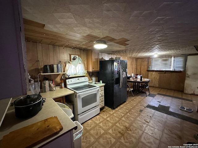 kitchen with black fridge, white range with electric stovetop, and wood walls