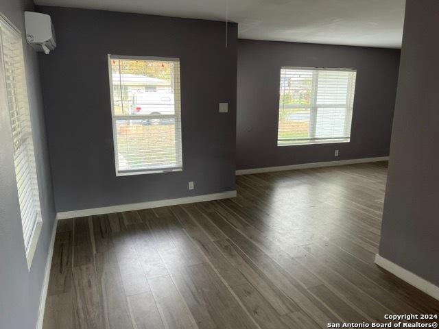 spare room with dark wood-type flooring and a wall mounted AC