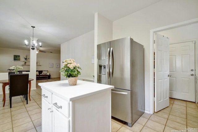 kitchen with stainless steel fridge, white cabinets, a kitchen island, hanging light fixtures, and light tile patterned flooring