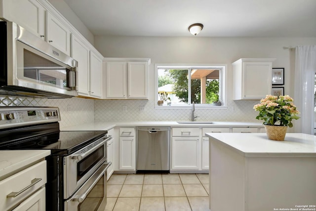 kitchen with white cabinets, sink, decorative backsplash, light tile patterned floors, and stainless steel appliances