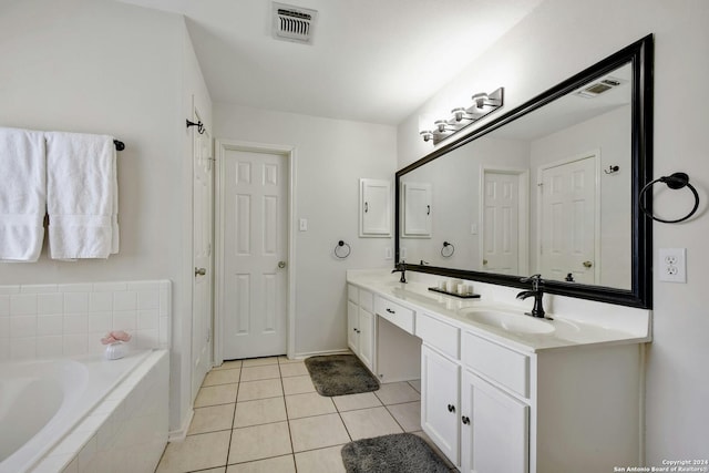 bathroom with tile patterned flooring, vanity, and tiled bath