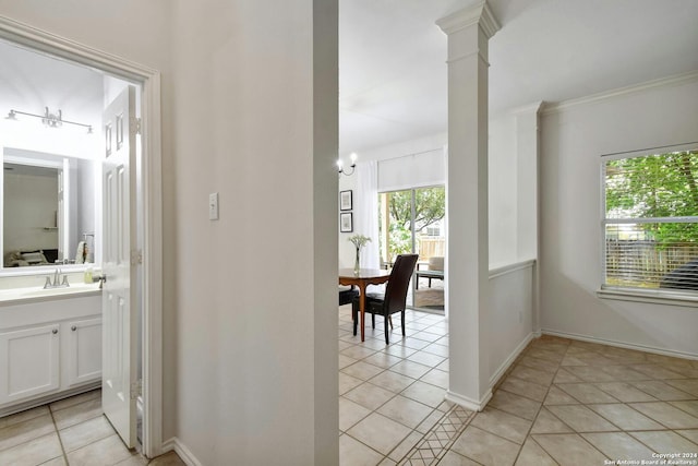 hall featuring ornate columns, crown molding, sink, and light tile patterned floors