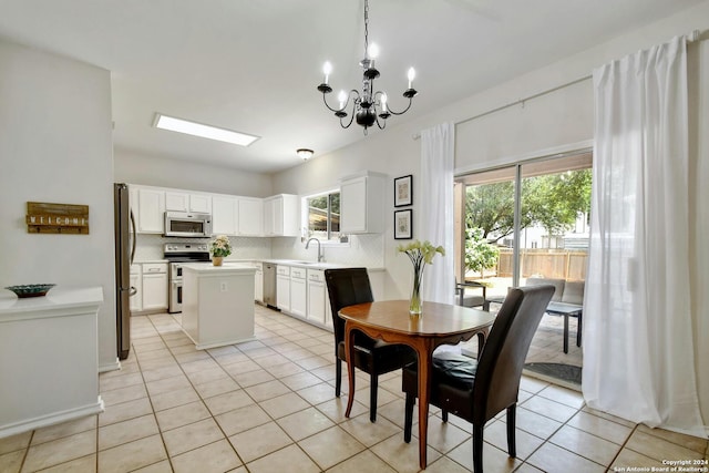 kitchen with appliances with stainless steel finishes, pendant lighting, white cabinets, a center island, and light tile patterned flooring