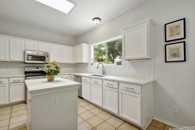 kitchen with white cabinets, appliances with stainless steel finishes, light tile patterned flooring, and sink